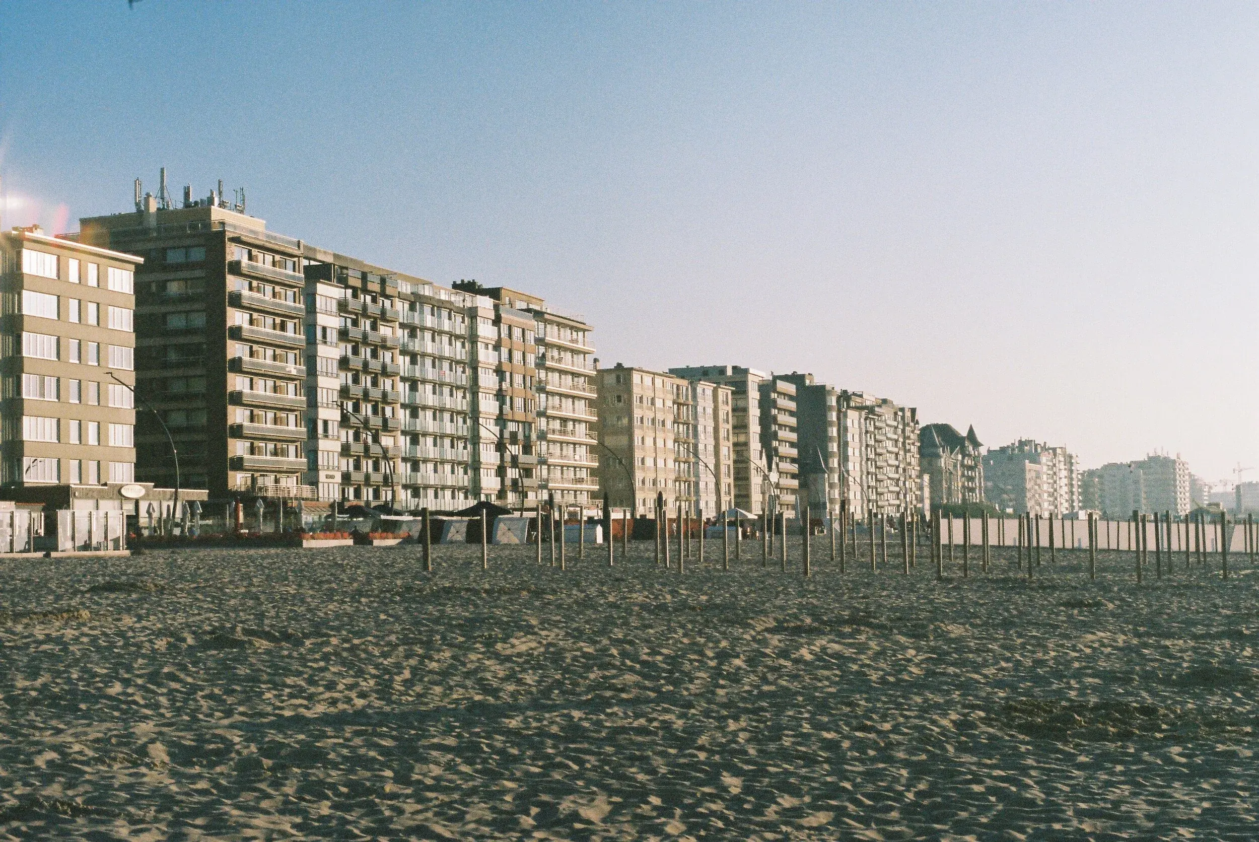 Bâtiments résidentiels le long d'une plage de sable sous un ciel clair.