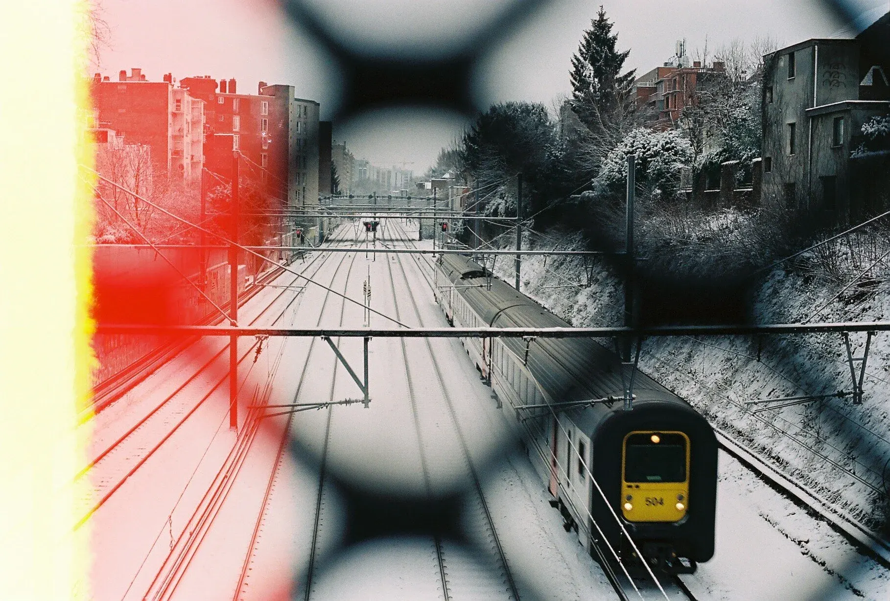 Trains sur des voies ferrées enneigées, vu à travers une vitre avec des traces de condensation